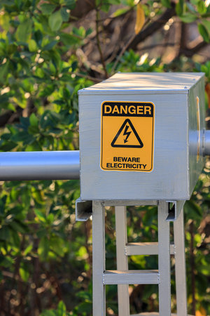 Danger beware electricity sign, Electrical Hazard High Voltage sign on metal box and tube, black triangle over yellow sign.の写真素材