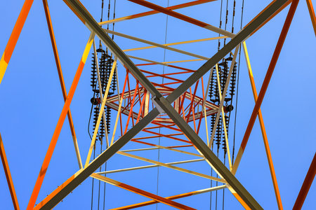 View from below of high voltage electric tower against with blue sky.