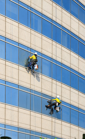 high rise building Window washers cleaning the glass facade of a modern building, skyscraper high risk work.の写真素材
