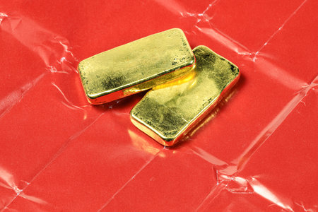 A stack of real shiny gold bars or gold ingots On the red paper used to wrap gold when trading...