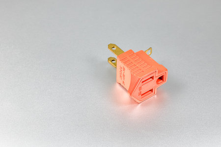 Orange plugs adapters for NEMA plug type B convert to type A with grounded contact isolated on white background.の写真素材
