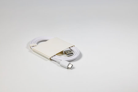 New white USB type charger cable in paper pack, compatible for many devices, wrapped in a spiral...
