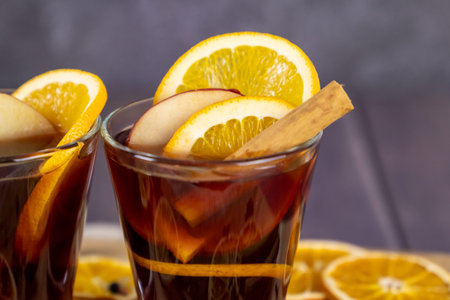 Mulled wine poured in glass cups placed on wooden table, winter alcohol drinks decorated with...