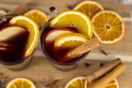 Mulled wine in glass cups , hot red wine alcohol drinks on wooden table decorated with cinnamon...