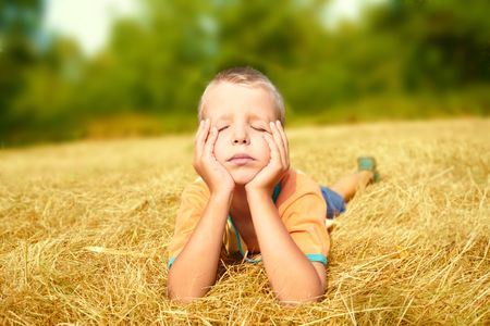 A carefree young boy laying on ground whith eyes shuttedの写真素材