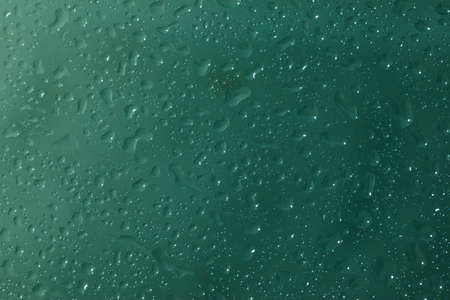 Macro shot of waterdrops on a glassplate with a darkgreen backgroundの写真素材