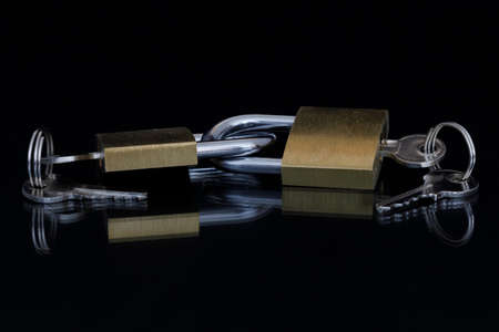 Two padlocks connected to each other with the key inserted and the spare key connected to the keyring.の写真素材