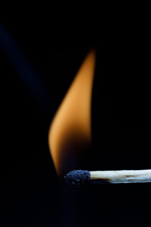Match burning with an orange flame against a black background