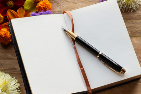 Floral arrangement on a wooden background with an open page and pen lying on the pages. Toning.