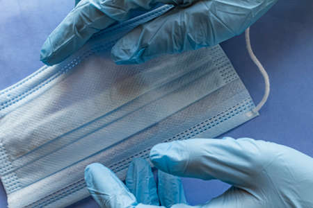 Gloved hands hold a medical mask.の写真素材