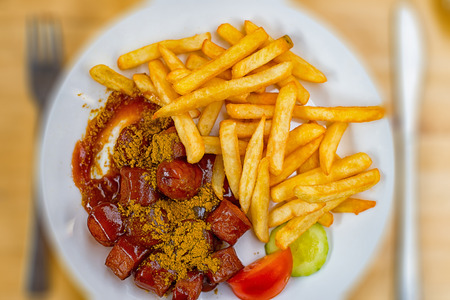 A plate full of curry sausage with French friesの写真素材