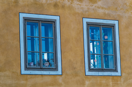 Two Wooden window on an old house with yellow facadeの写真素材