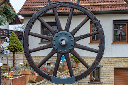 A Wheel of a carriage is hanging on the gate for decorationの写真素材