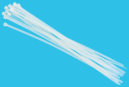 Nylon cable ties isolated on  blue background with no shadows. Cable tie is designed for bandaging bundles of wires.の写真素材