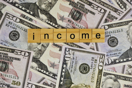 The financial concept of income tax is visually represented by colorful letter blocks on dollar bills.の写真素材