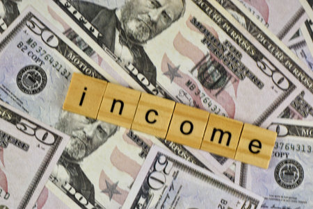 The financial concept of income tax is visually represented by colorful letter blocks on dollar bills.の写真素材