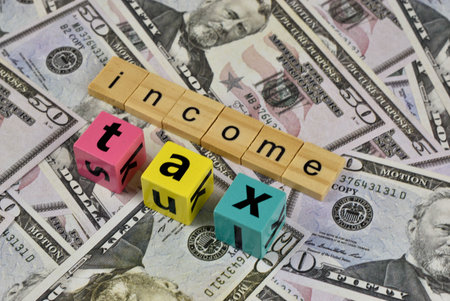 The financial concept of income tax is visually represented by colorful letter blocks on dollar...