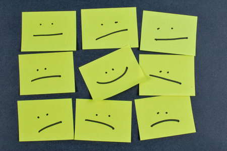 Nine yellow cards with varied facial expressions on dark background, illustrating a range of emotions through minimalistic design and layout.の写真素材