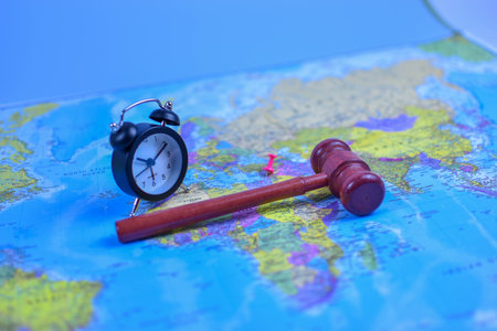 Red gavel and black stopwatch on world map symbolize global justice, legal urgency, and international decision-making across geographic boundaries.の写真素材