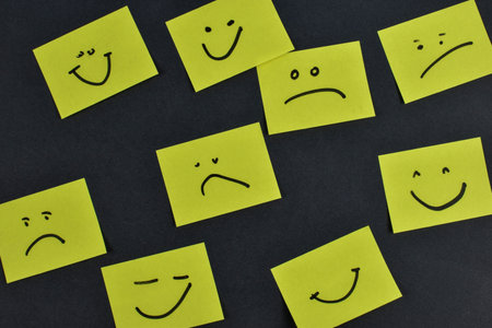 Nine yellow cards with varied facial expressions on dark background, illustrating a range of...
