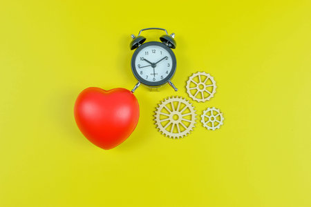 Red heart and four white gears on yellow surface represent emotional value linked to mechanical...