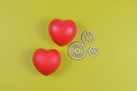 Red heart and four white gears on yellow surface represent emotional value linked to mechanical systems, process, or structured interaction.の写真素材