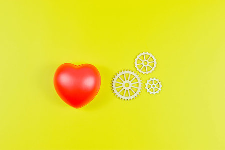 Red heart and four white gears on yellow surface represent emotional value linked to mechanical...