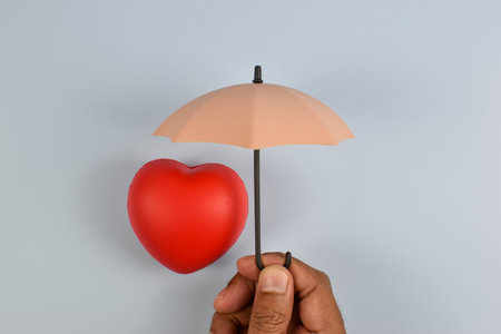 Hand shelters red heart with symbolic gesture representing emotional protection, care, and safeguarding love or vulnerability.の写真素材