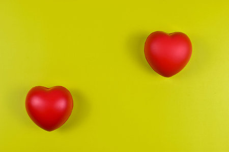 Two red hearts on yellow surface represent emotional value.