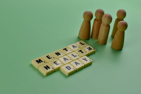 Wooden figurines face tiles spelling Mental Health Day, symbolizing collective awareness and support for emotional well-being.の写真素材
