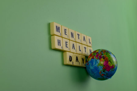 Scrabble tiles spell Mental Health Day beside globe, symbolizing global recognition of emotional well-being and mental health awareness.の写真素材