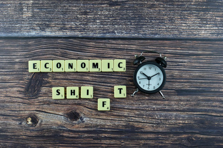 Scrabble tiles spell Economic Shift on wood, symbolizing transformation in financial systems or market conditions through intersecting wordplay.の写真素材