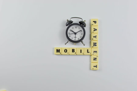 Clock above intersecting Scrabble tiles spelling Mobile Payment, highlighting time-sensitive nature...