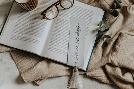 Hygge flatlay photo of a book, bookmark, sweater and reading glassesの写真素材