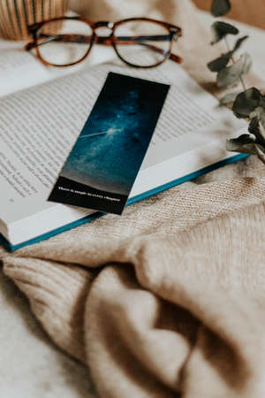 Hygge flatlay photo of a book, bookmark, sweater and reading glassesの写真素材