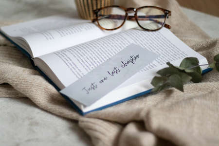 Hygge flatlay photo of a book, bookmark, sweater and reading glassesの写真素材