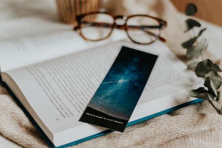 Hygge flatlay photo of a book, bookmark, sweater and reading glassesの写真素材