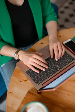 Close-up of female hands typing on laptop keyboard in cafe.の写真素材