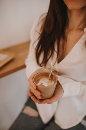 Close-up of a woman holding a cup of cappuccinoの写真素材