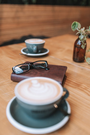 Coffee cup and eyeglasses on wooden table in coffee shopの写真素材