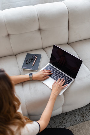 overhead view of businesswoman working with laptop on sofa at homeの写真素材