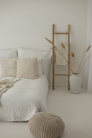 interior of modern bedroom with white pillows on bed and wooden ladderの写真素材