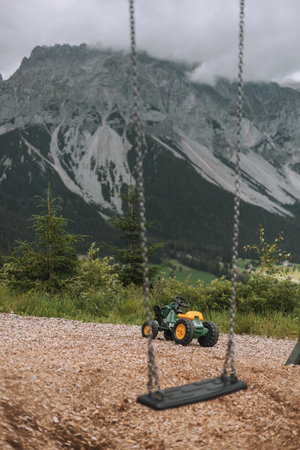 A yellow toy tractor on a swing in the Dolomites.の写真素材