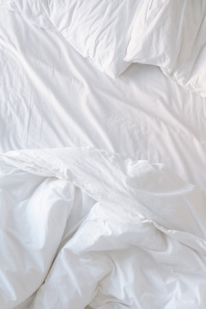White bedding sheets and pillows on the bed, close upの写真素材