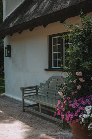 Wooden bench in front of a house with a thatched roofの写真素材