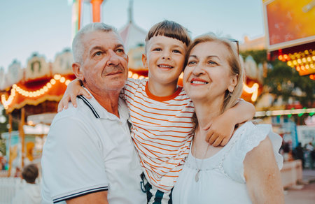 Senior couple exiting carousel at amusement park with there grandson