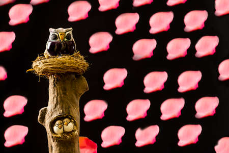 Close-up of a figure of a lucky owl and two baby owls on a wooden log.The photograph has a space to write the text of your choice.The photo is taken horizontally and has a repeating pattern.の写真素材