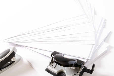 Photograph of some fan-shaped sheets of paper, a stapler and a hole punch for sheets of paper on a...