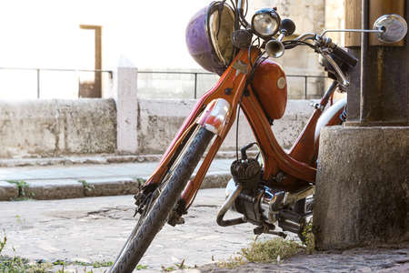 old and very old motorcycle leaning on a column in the city of Leon in Spainの写真素材