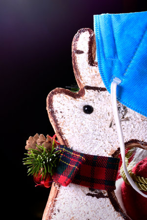 Photo of a white cork Christmas reindeer with a typical red bow and a blue mask.The photograph is taken in a studio on a black background and in vertical format.の写真素材